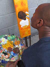 Herold Alvares mouth paints on canvas stretched on an old wooden crutch